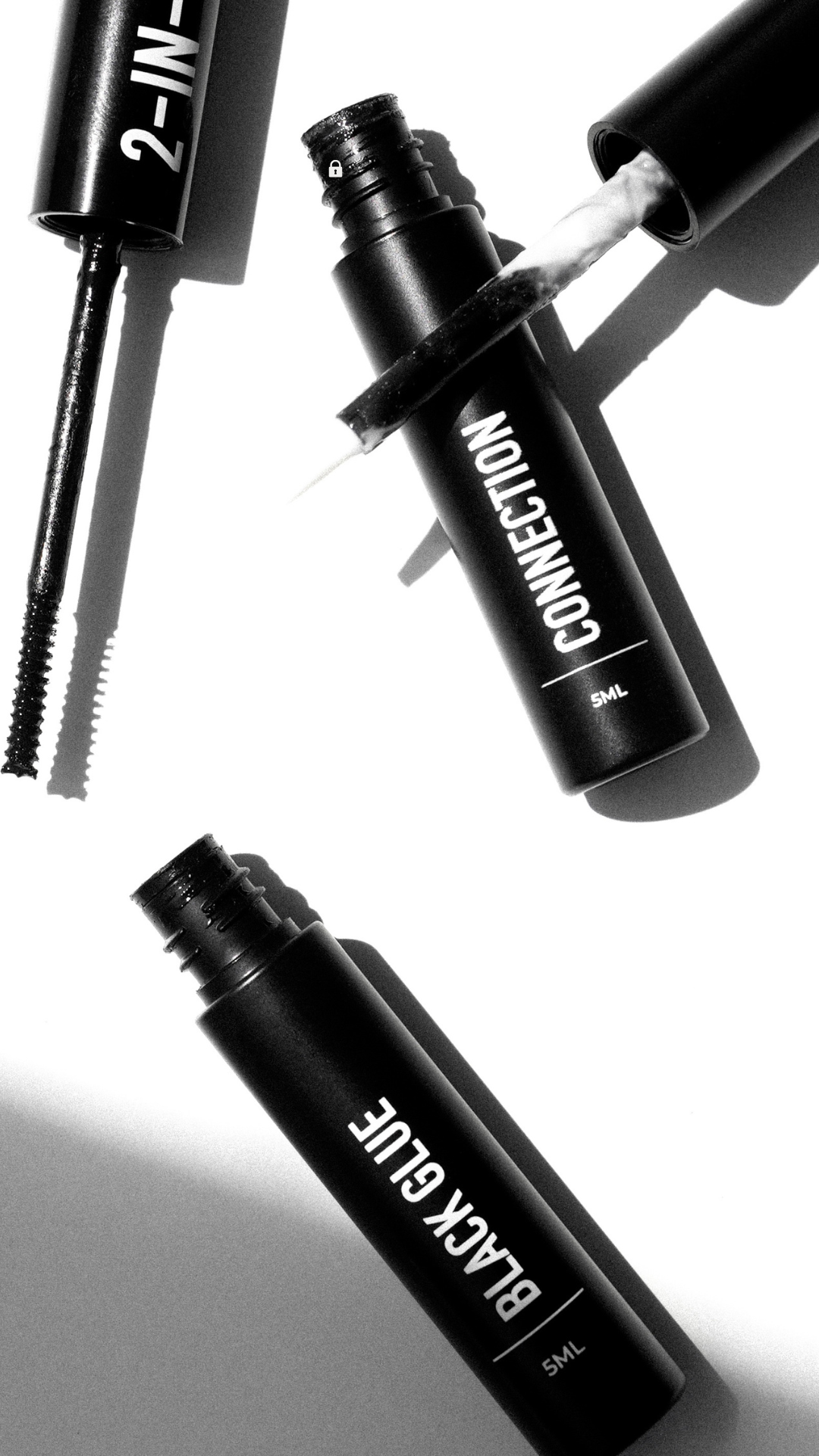 Flat lay of Citizen Lash 2 in 1 DIY lash adhesive showing the black glue wand applicator and Connection clear glue brush tip, with dual ended packaging displayed against a light background.